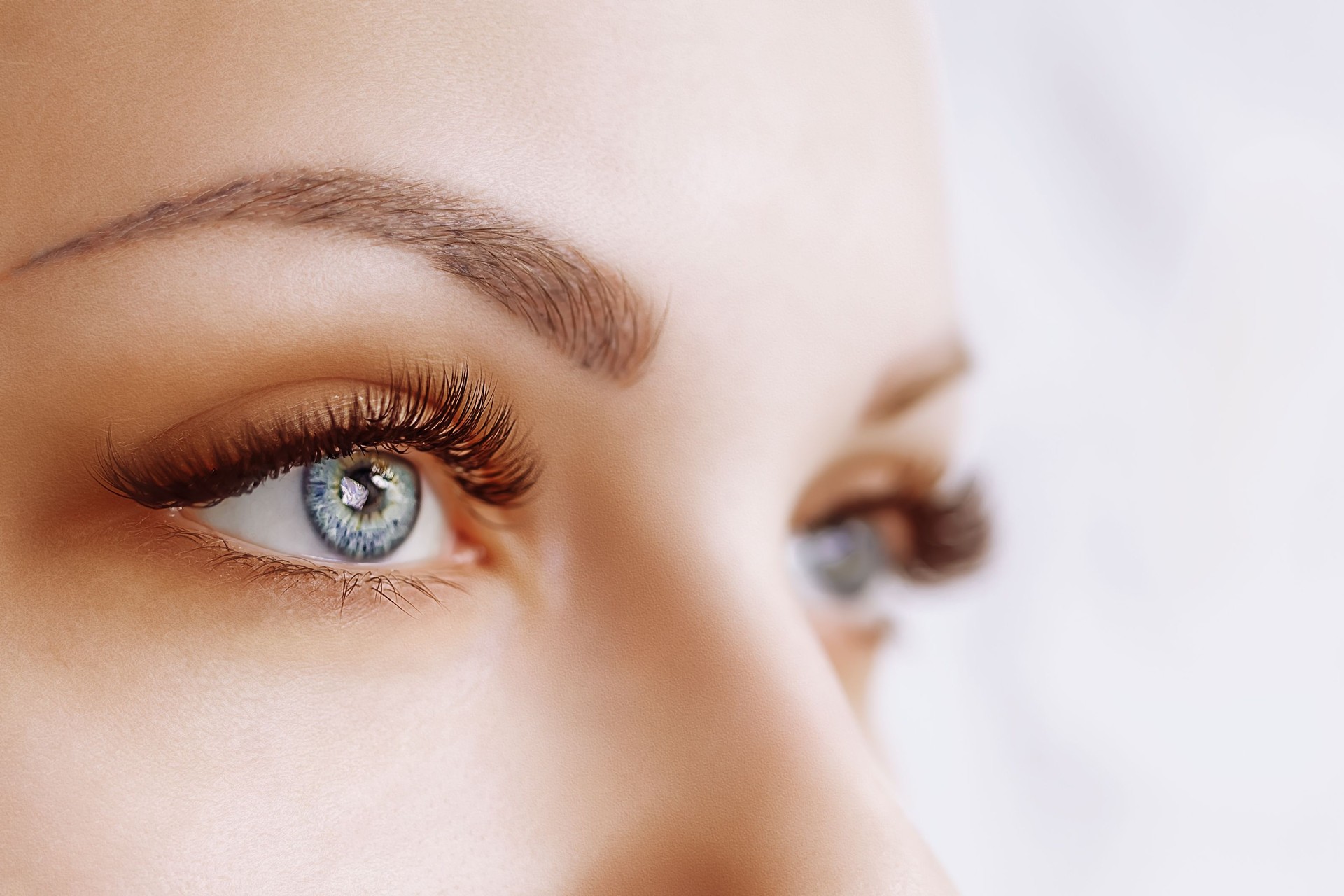 Eyelash Extension Procedure. Woman Eye with Long Eyelashes. Close up, selective focus